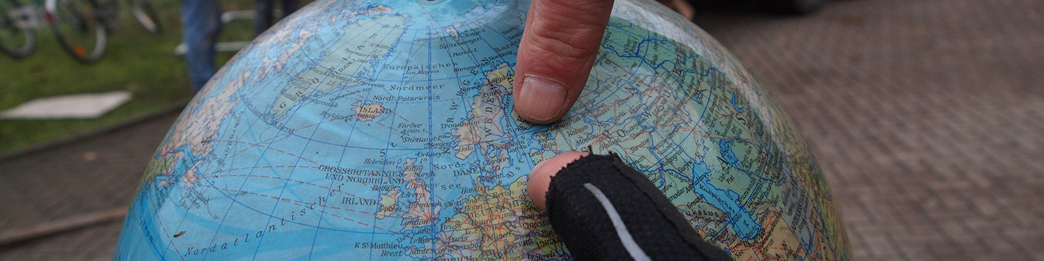 Zwei Finger zeigen auf einem Globus auf das Land Litauen.